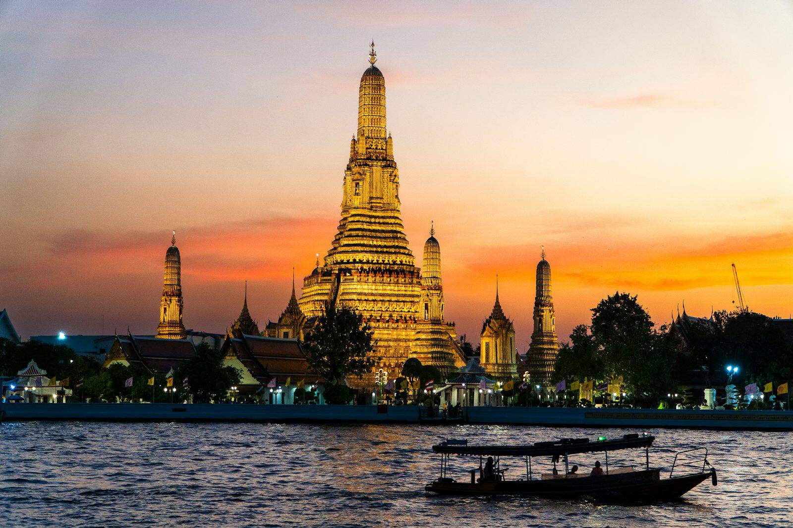 Wat Arun glowing at sunset with a boat on the Chao Phraya River