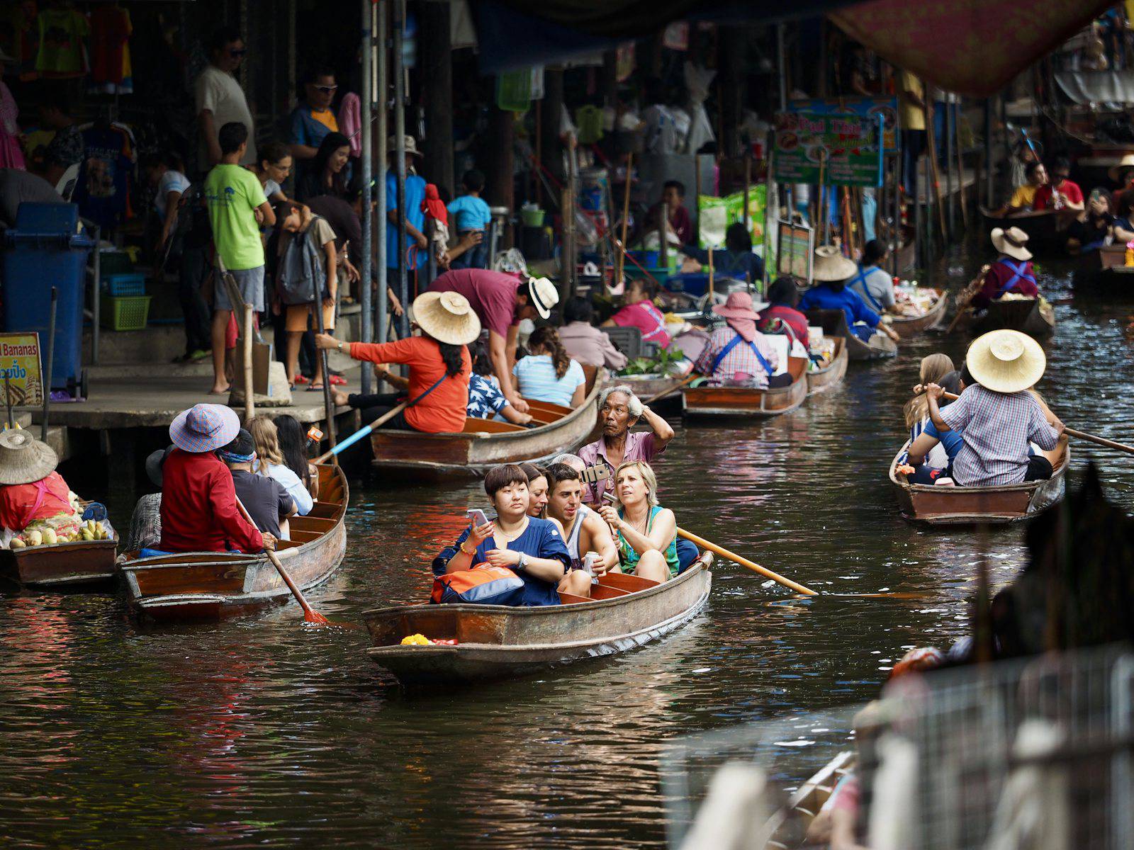 Visitors riding paddle boats through a floating market near Bangkok