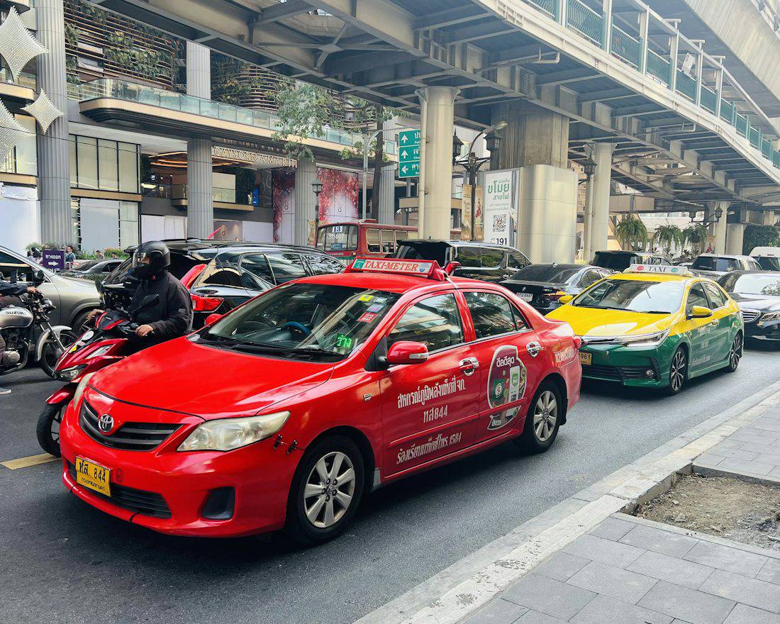 Taxis on a busy Bangkok road under the expressway