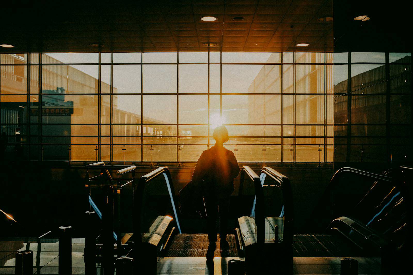 Traveler with luggage inside an airport terminal at sunrise