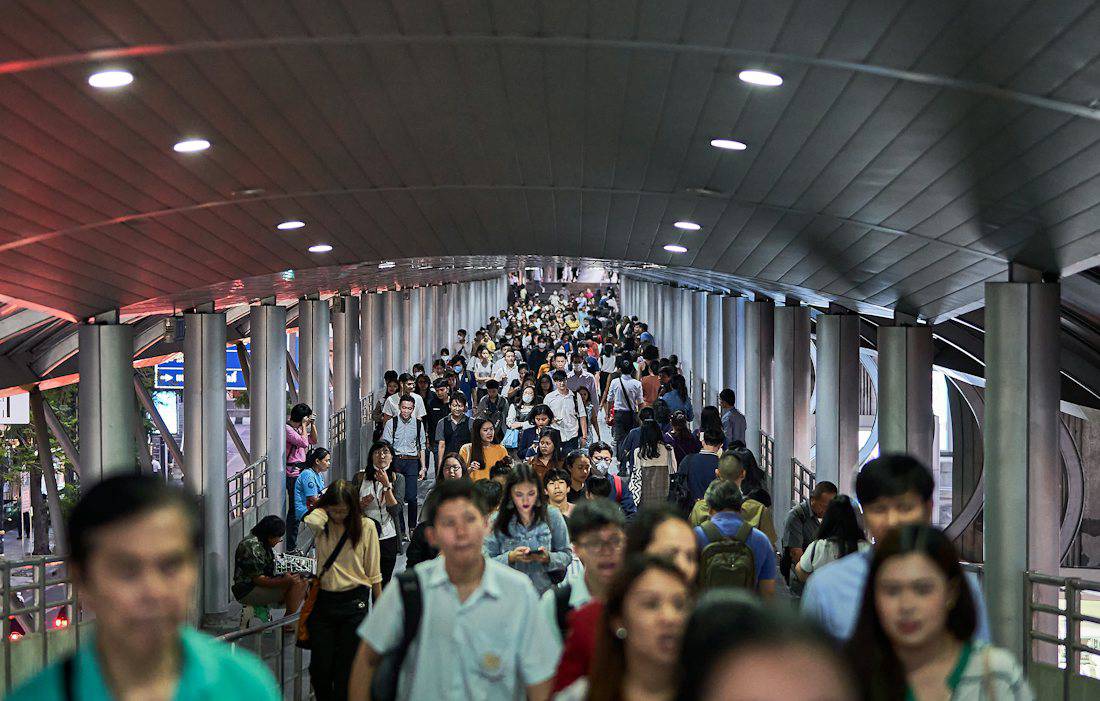 Commuters on an elevated walkway near a Bangkok train station