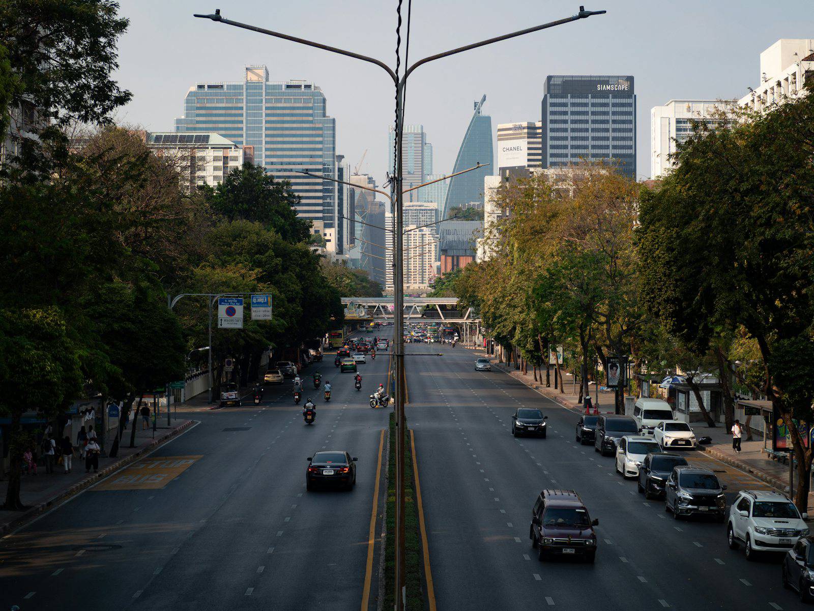 Cars driving on a wide city street with buildings.