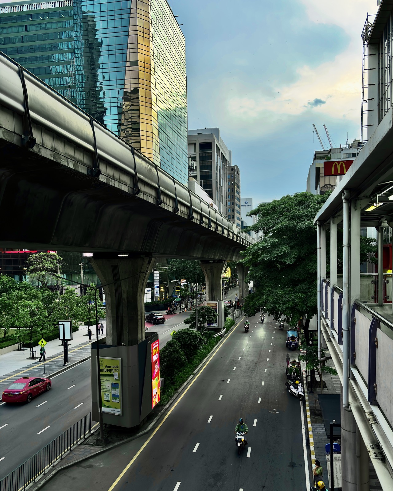Silom Road in Bangkok seen from a skywalk, with the BTS Skytrain viaduct overhead